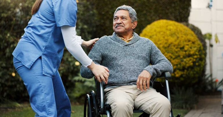 A caregiver chatting with an older adult in a bright, well-kept common area.